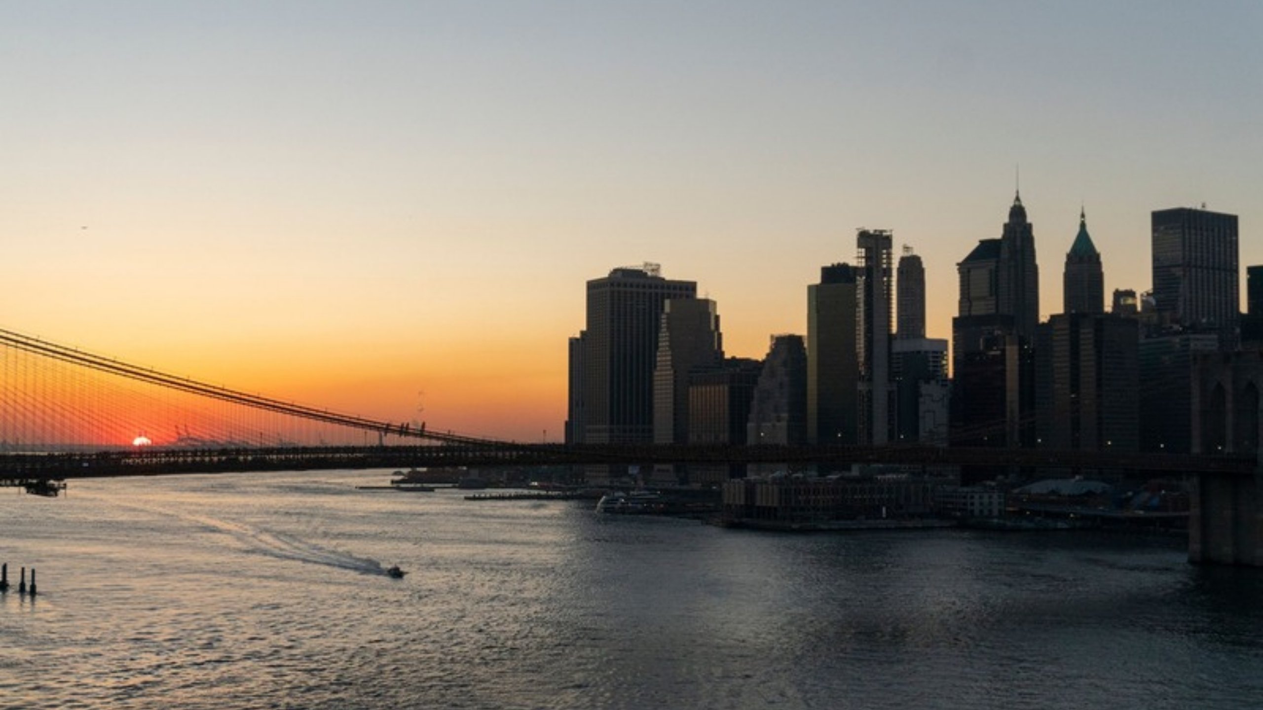 The Manhattan skyline and Brooklyn Bridge at sunset over the East River