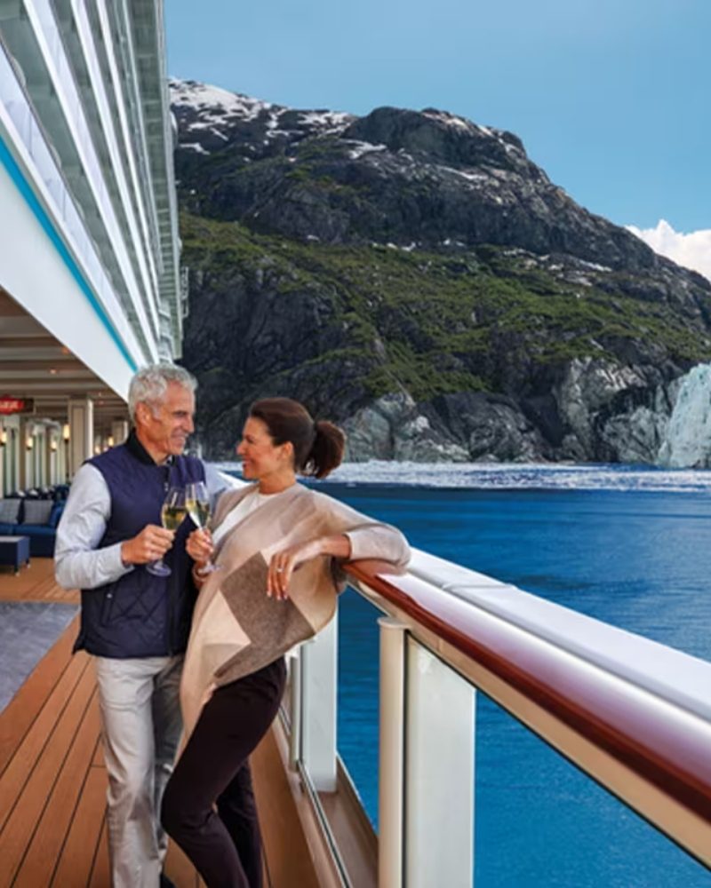 A couple toasting on a ship's deck as it sails past a glacier in Alaska