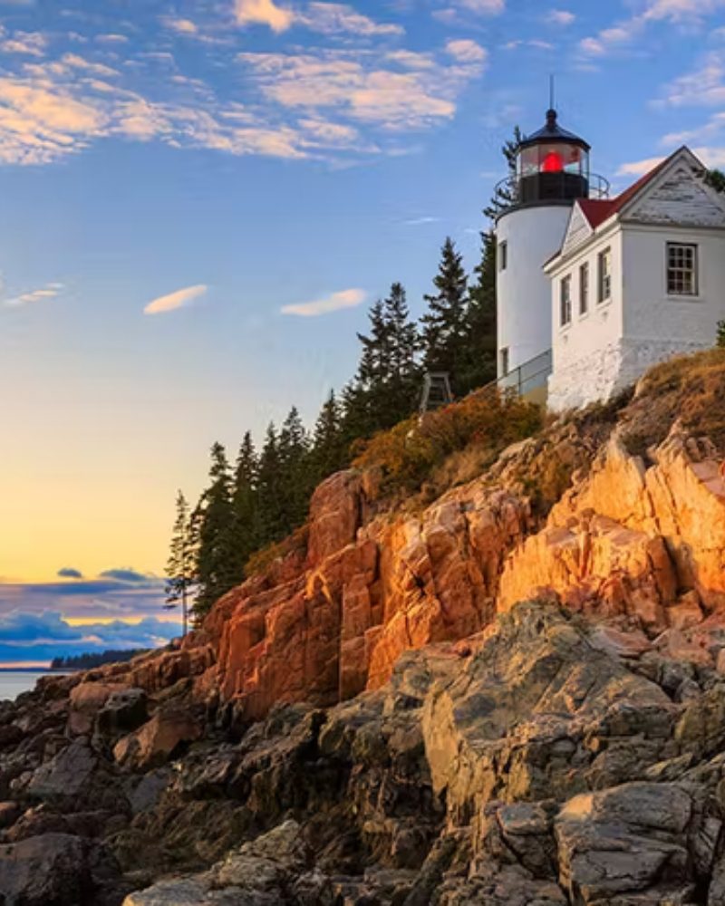 A lighthouse on the rocky coast of Maine at sunset
