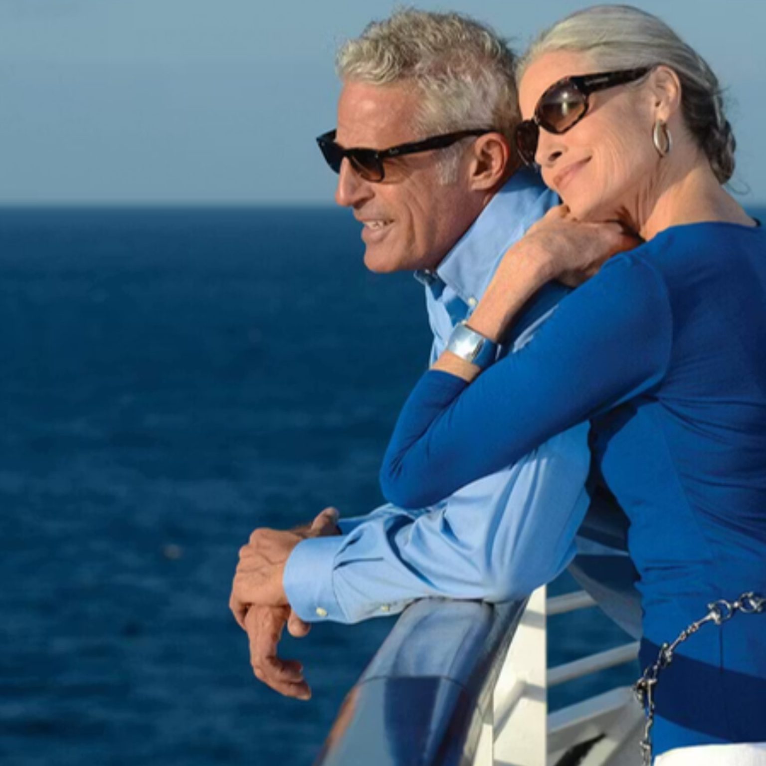 A couple leaning on the deck rail of an Oceania Cruises ship at sea