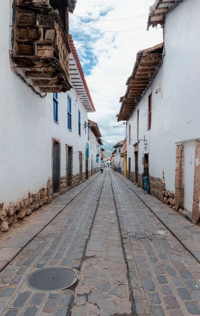 A cobblestone lane with colorful buildings in Cusco