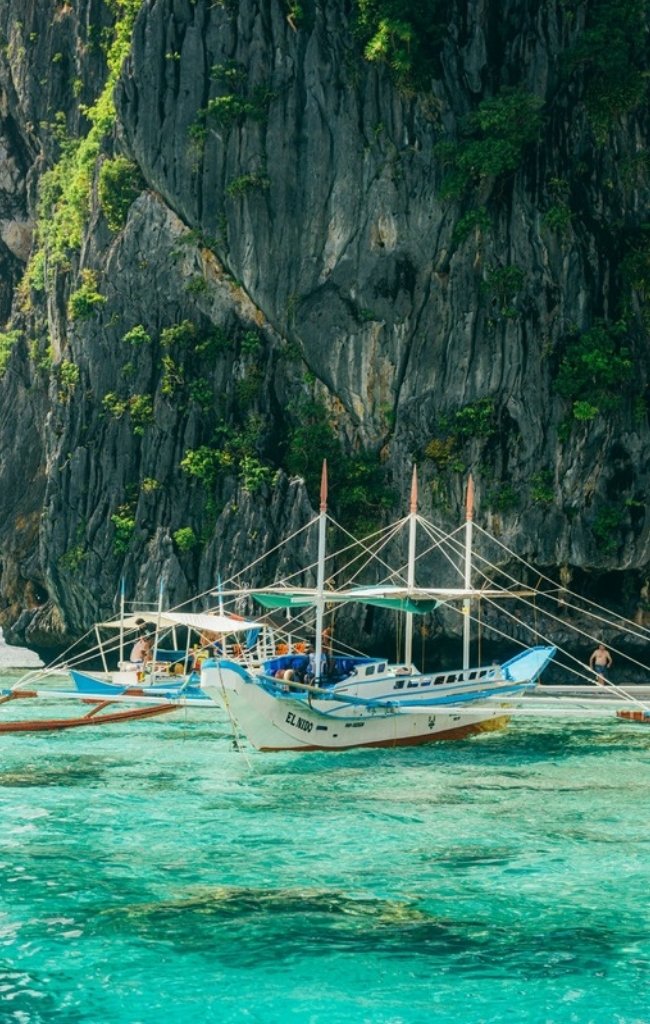 Outrigger boats near limestone cliffs in turquoise water