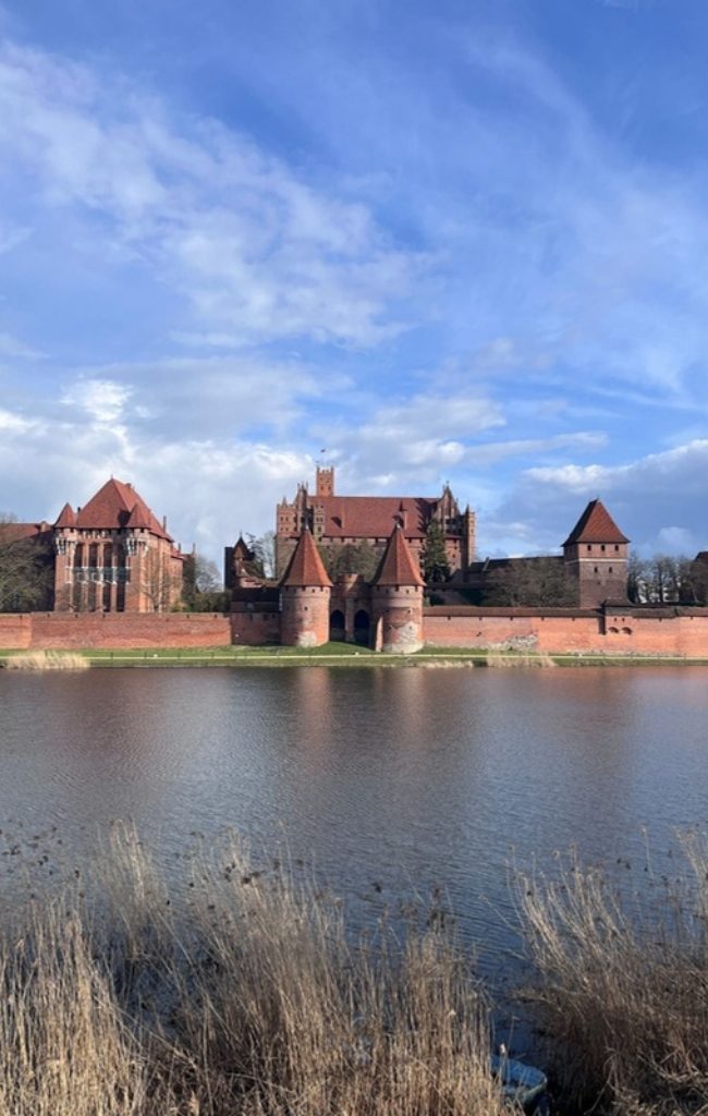 Malbork Castle reflected in the river under a blue sky