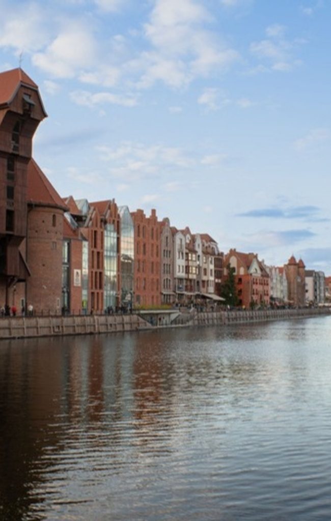 Historic merchant houses and a tall ship on the Gdansk waterfront