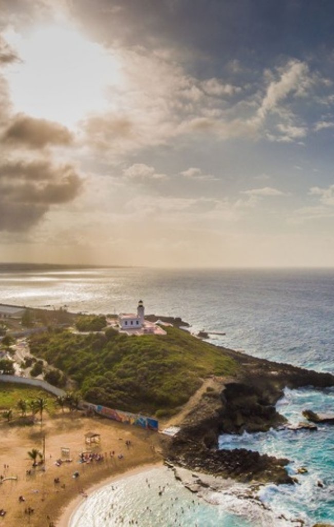 A lighthouse on a green point above the sea on the west coast of Puerto Rico