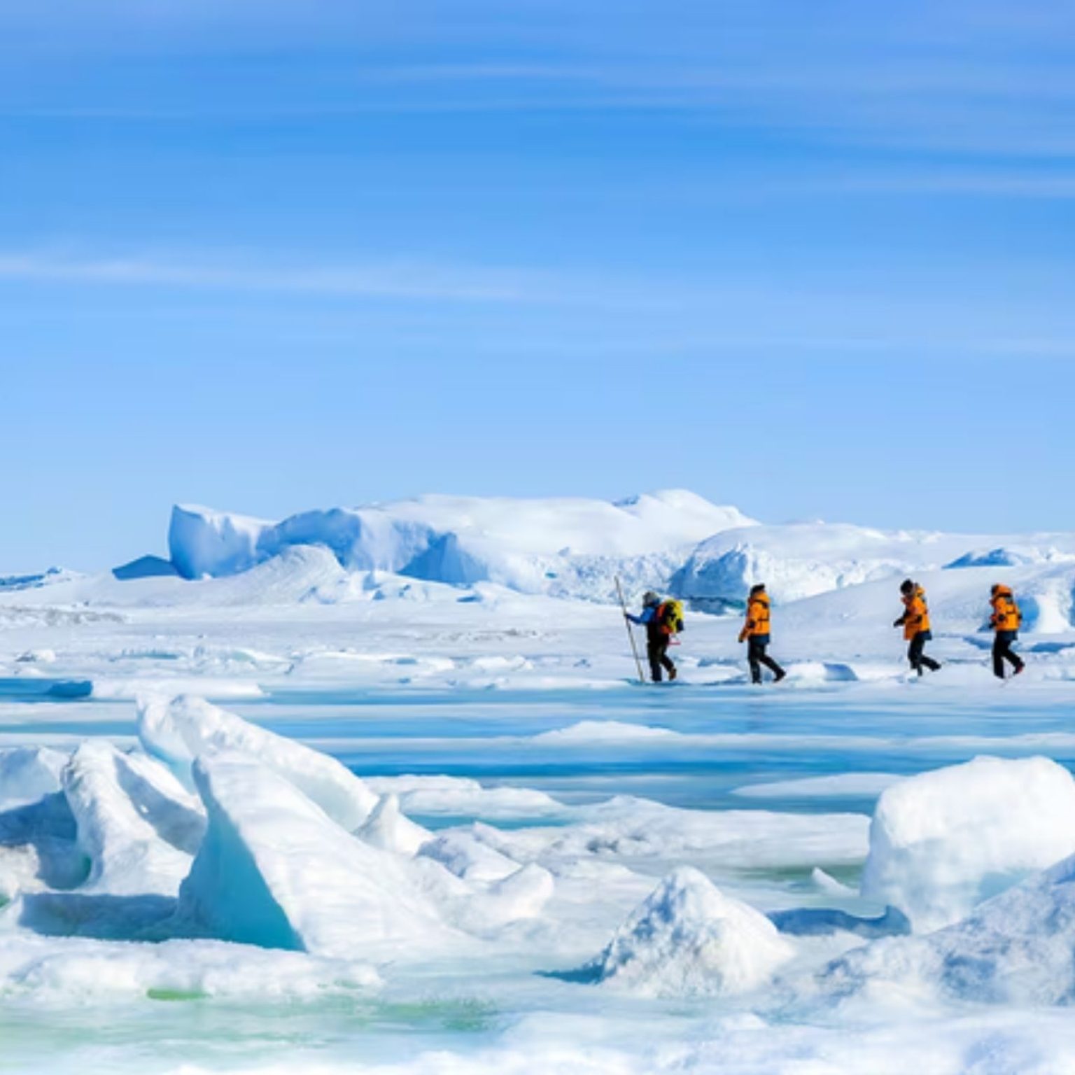 Travelers in orange parkas walking across polar sea ice