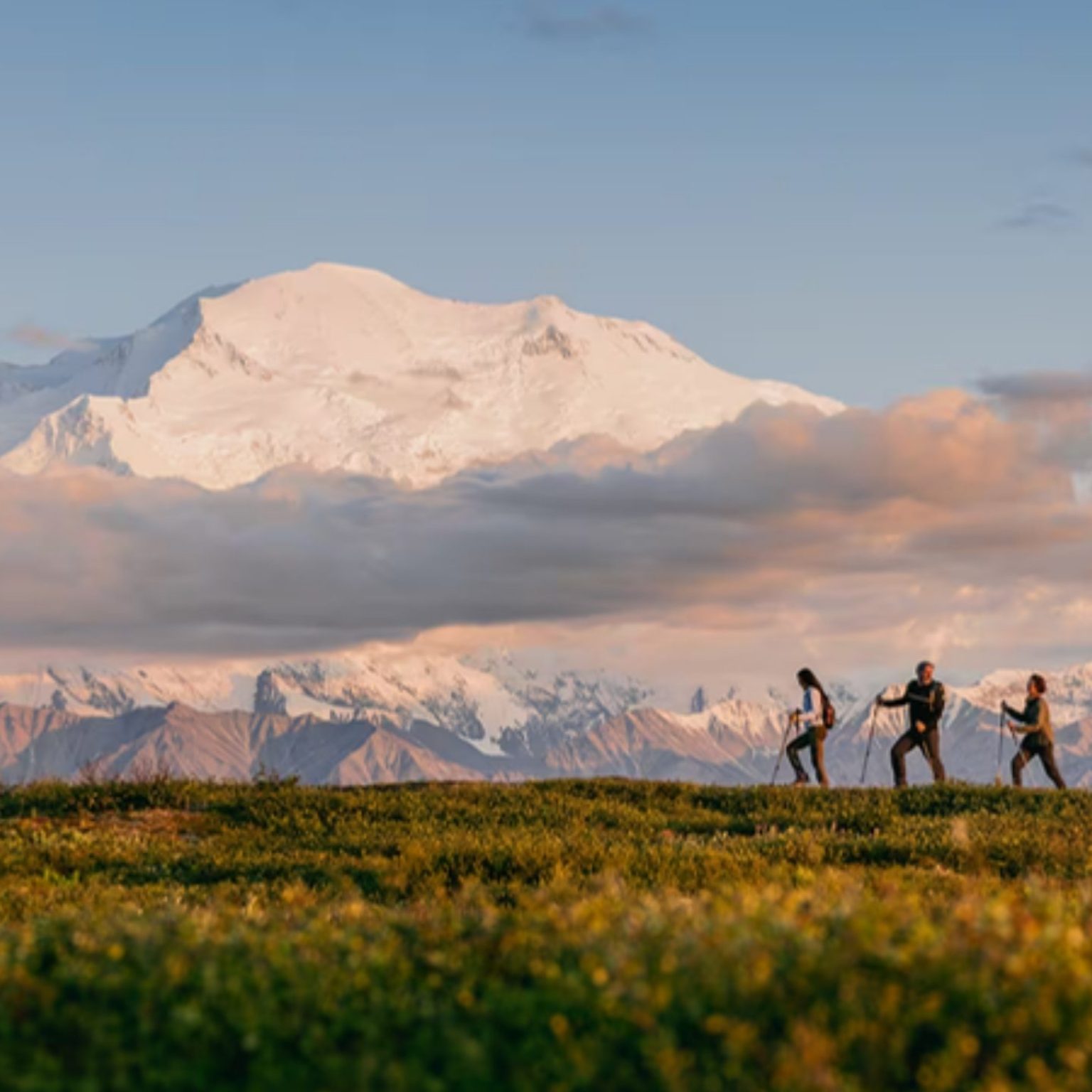 Hikers on a ridge below Denali at sunset