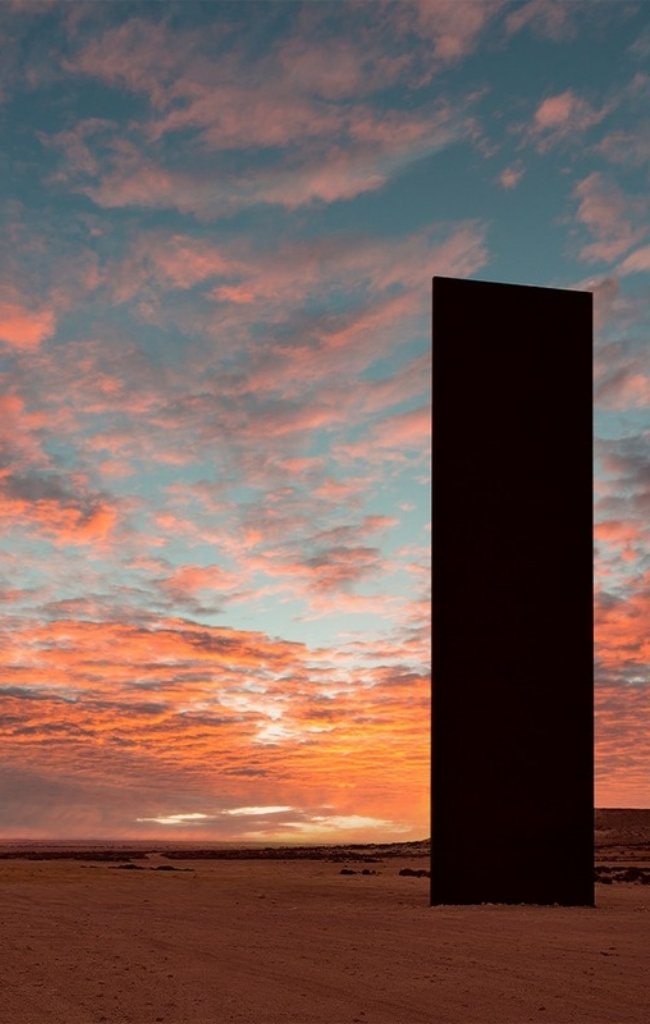 Tall steel sculpture plates standing in the desert at sunset