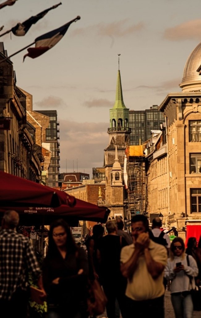 A busy street in Old Montreal with a green church spire