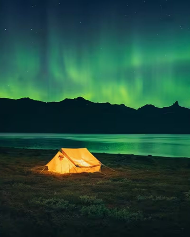A lit tent under the Northern Lights in Greenland