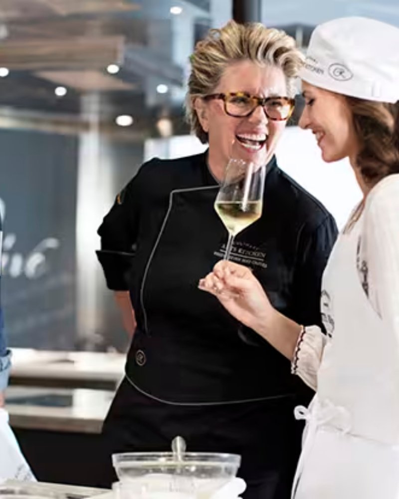 A chef and guest sharing wine during a cooking class at sea