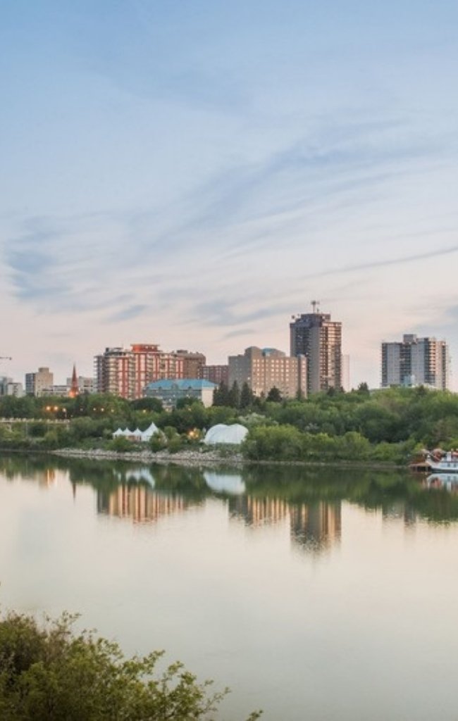 The Saskatoon skyline reflected in the South Saskatchewan River at dusk