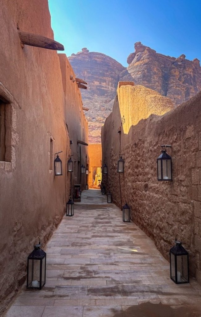 A lantern-lit lane in AlUla Old Town below desert cliffs