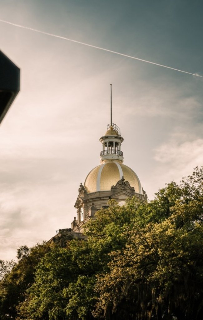 The gold dome of Savannah City Hall above the trees