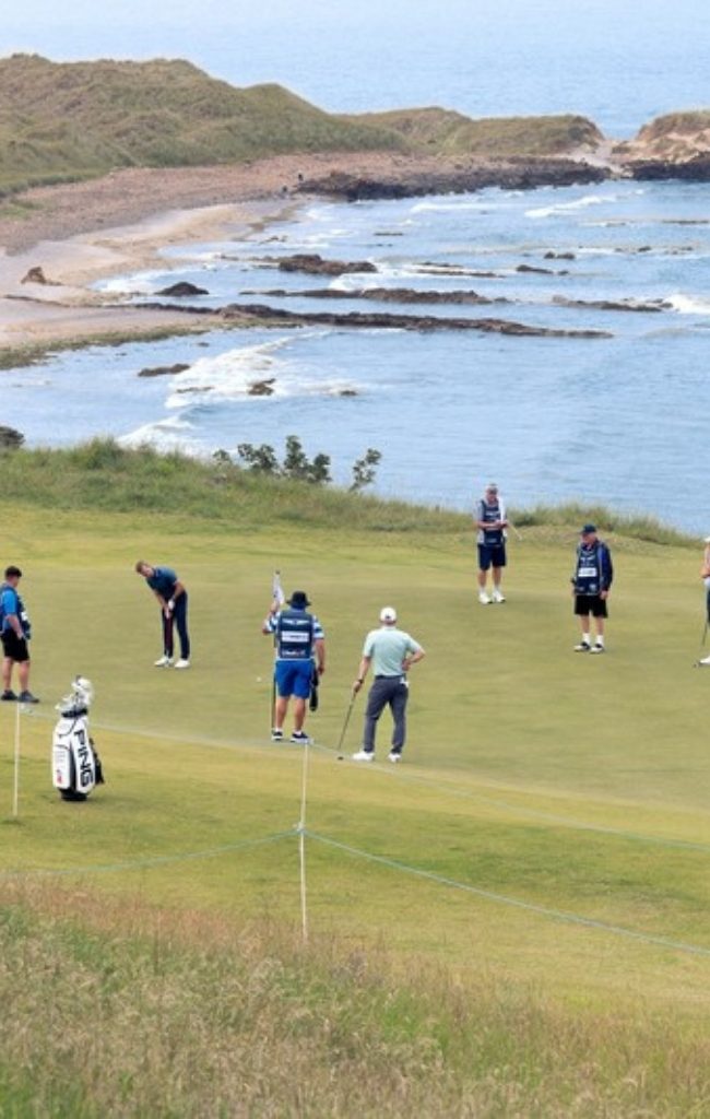 Golfers on a coastal links course overlooking the sea in Scotland