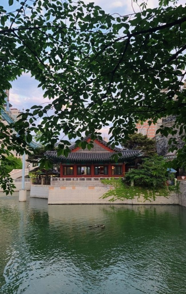 A traditional hanok pavilion beside a pond in summer