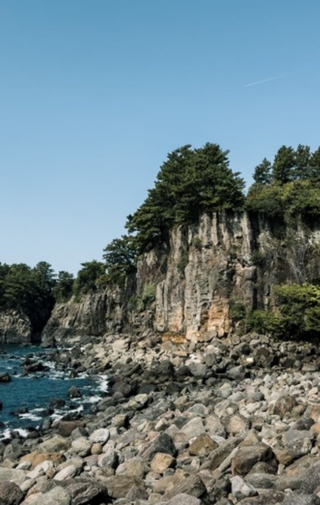 Jeongbang Waterfall falling onto the rocky shore of Jeju Island