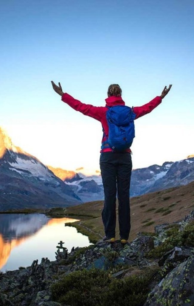 A hiker at the Riffelsee lake below the Matterhorn at sunrise