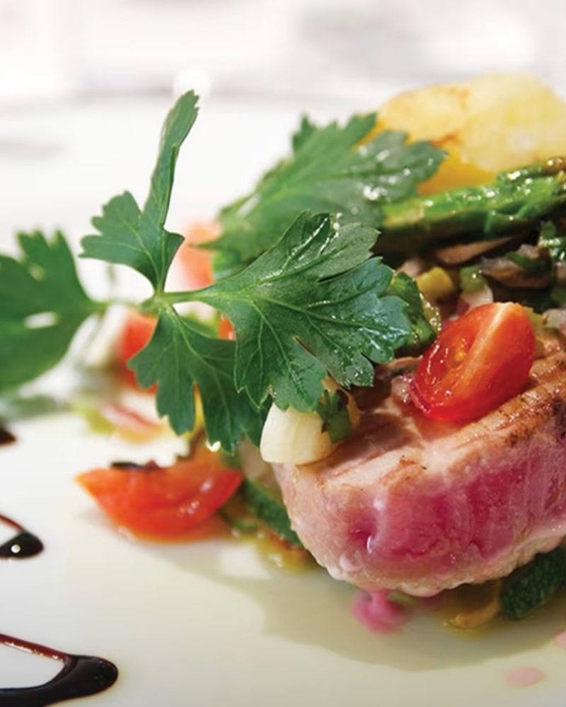 A plated seared tuna dish with fresh herbs