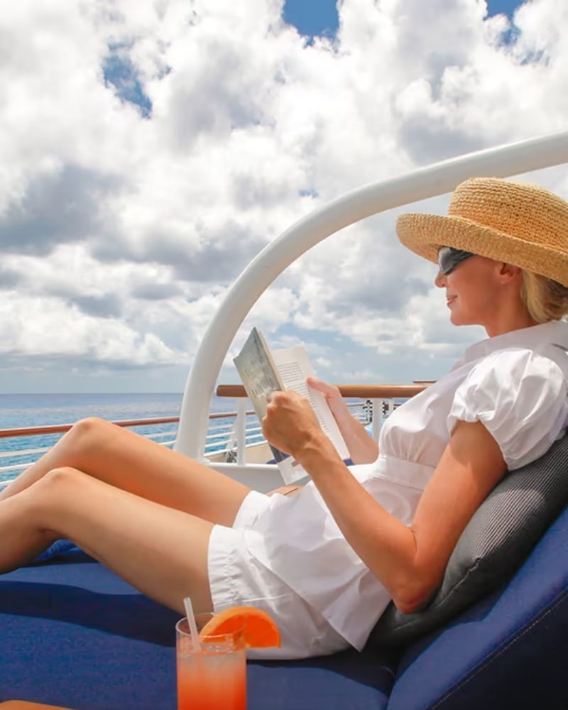 A guest reading on a deck daybed overlooking the sea