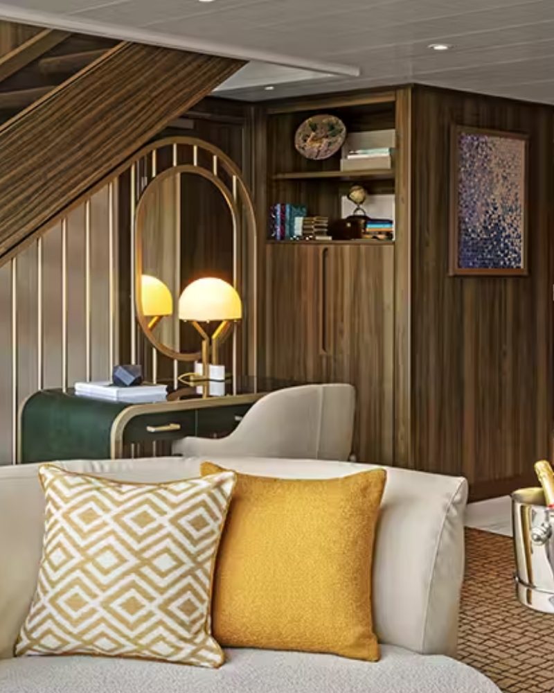 A Seabourn suite with a sofa, vanity and Champagne on ice