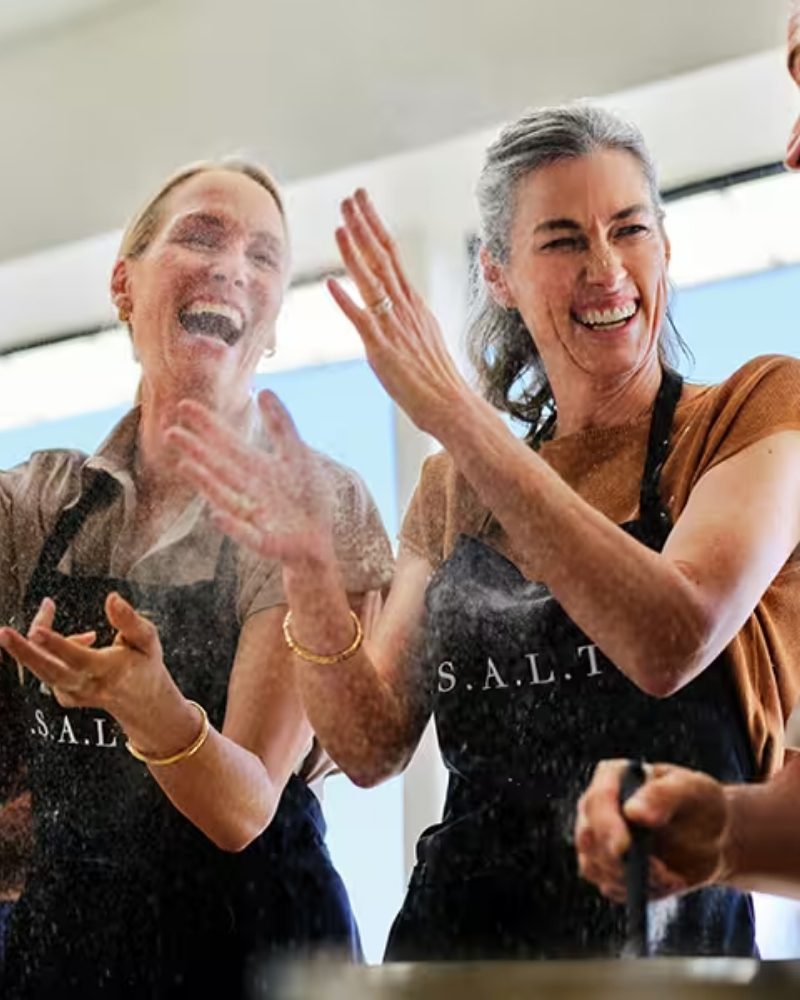 Guests laughing during a S.A.L.T. cooking class