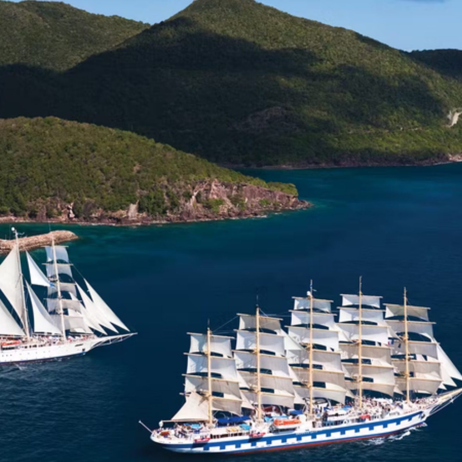 Star Flyer and Royal Clipper under sail off a green Caribbean island