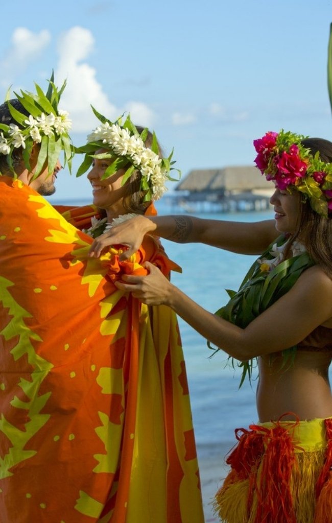 Dancers in flower crowns greeting a visitor by the lagoon