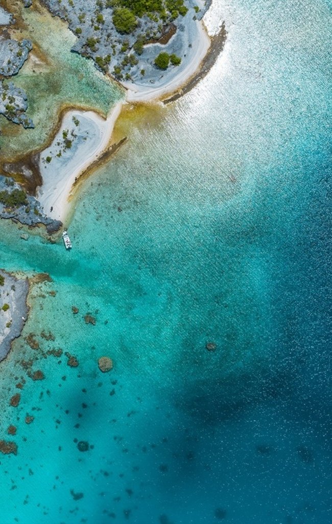 Aerial view of a coral atoll and clear lagoon in the Tuamotu Islands