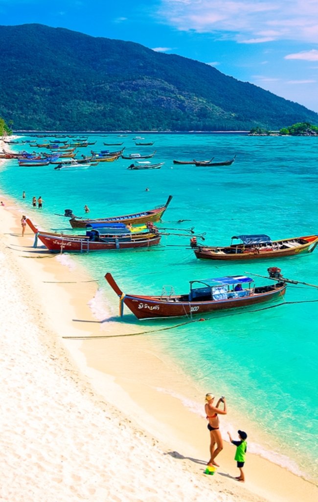 Longtail boats on a white sand beach in the Andaman Sea