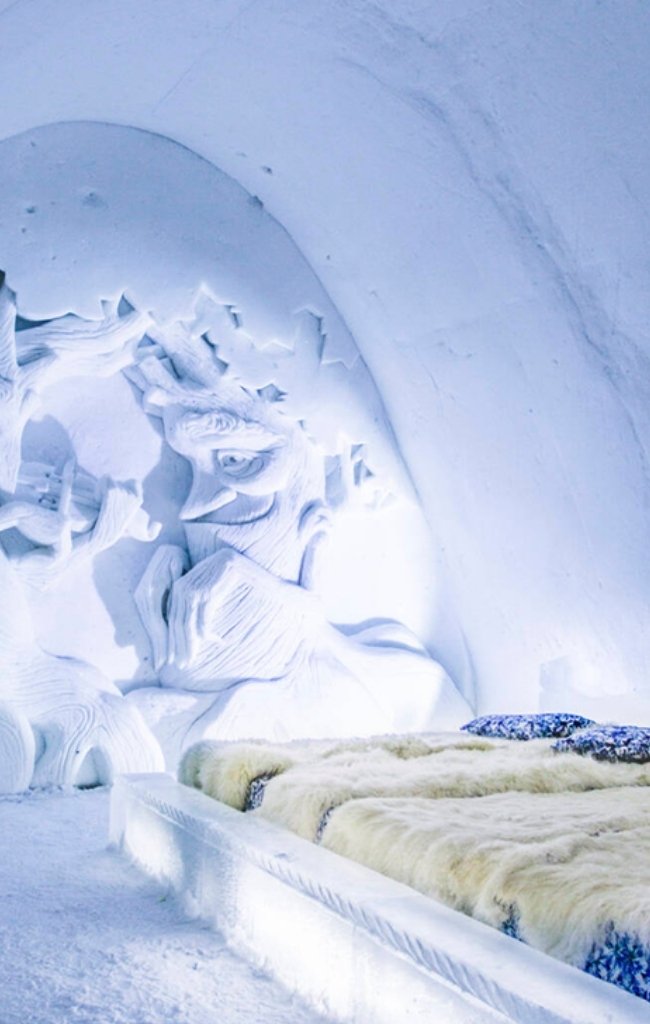 A carved snow suite with a fur-covered bed in a Finnish snow hotel