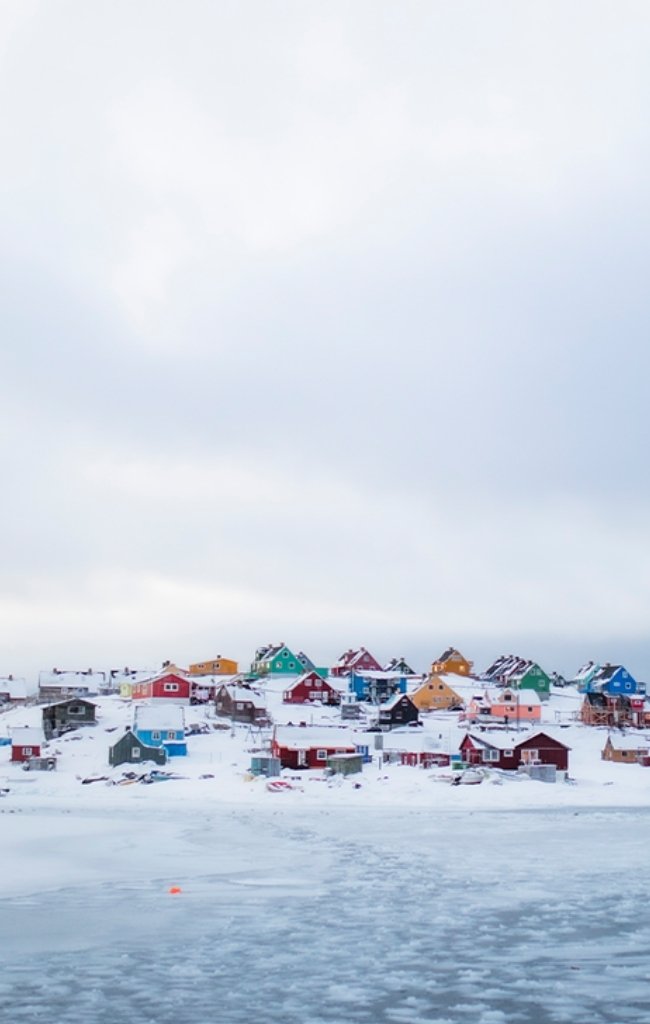 Colorful wooden houses on a snowy shore in Greenland