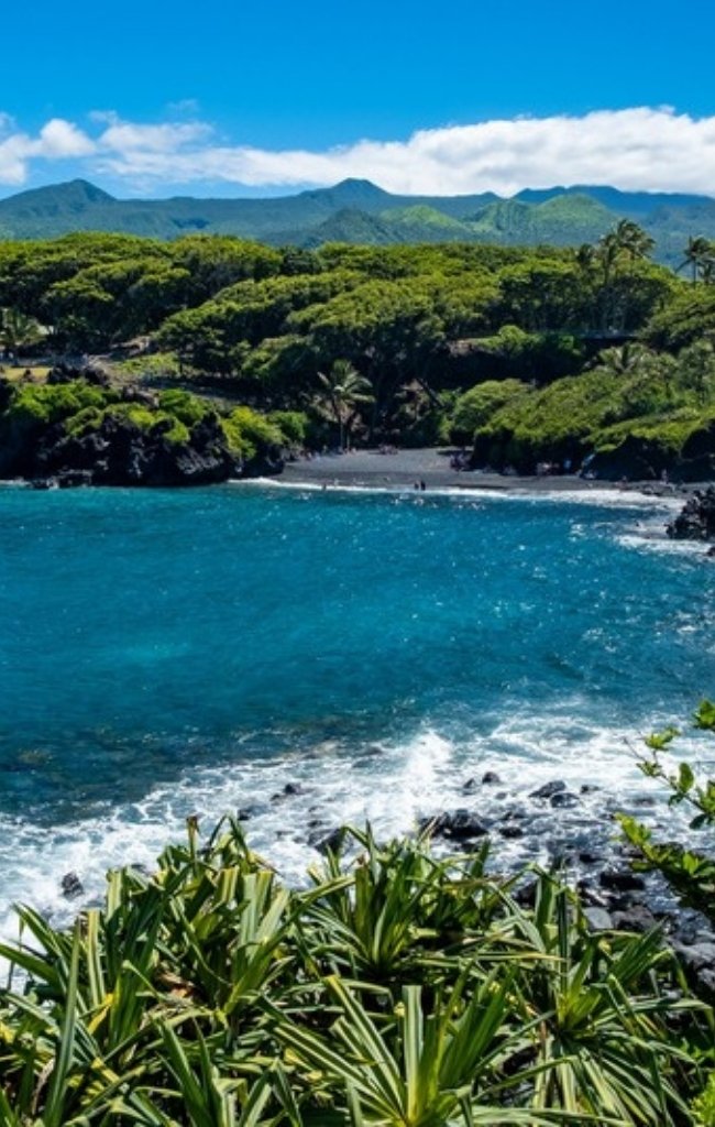 Green hills and a black sand beach at Hana Bay on Maui