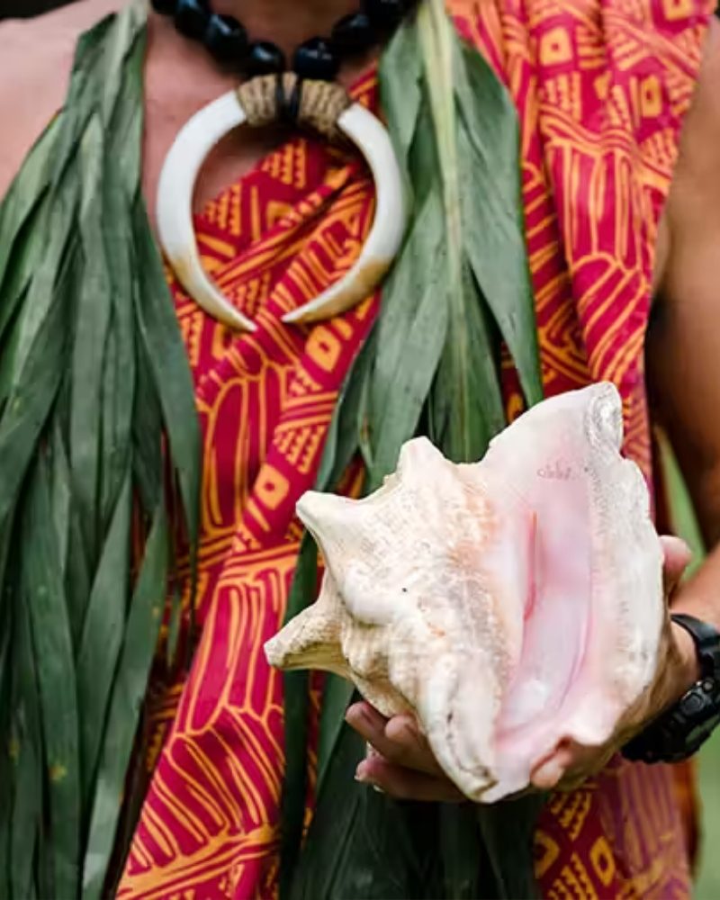 A Hawaiian host holding a conch shell