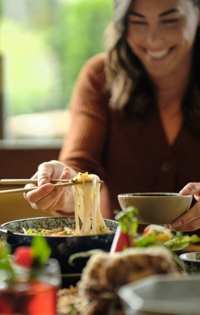 A traveler sharing a meal of noodles and fresh greens
