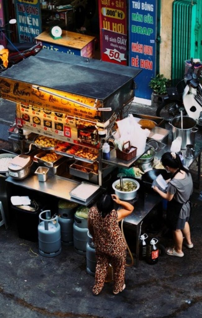 Two women preparing food at a Vietnamese street food stall