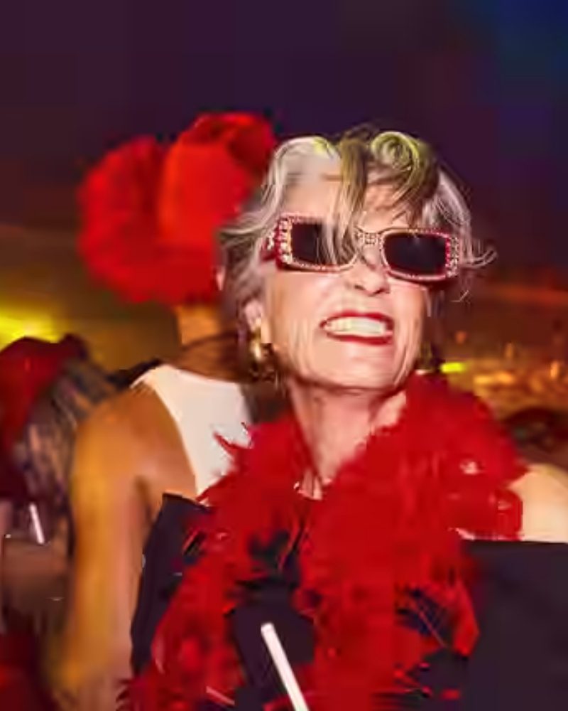 A guest in red sunglasses and a feather boa at Scarlet Night